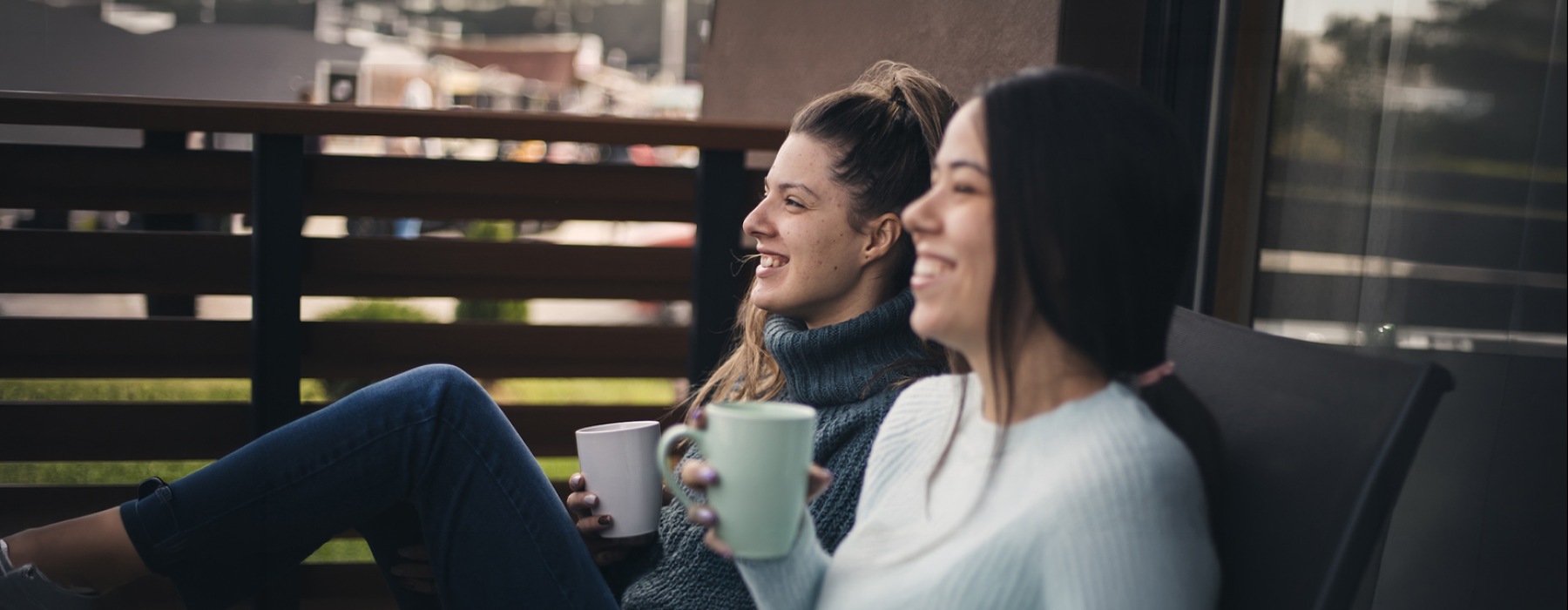 a couple of women sitting on a bench and drinking coffee